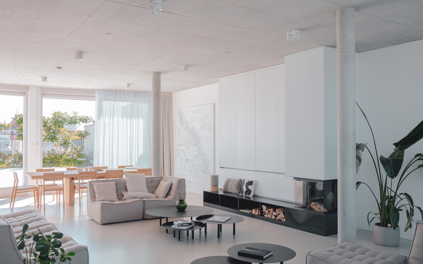 Modern living and dining area with sofas, dining table, and fireplace.