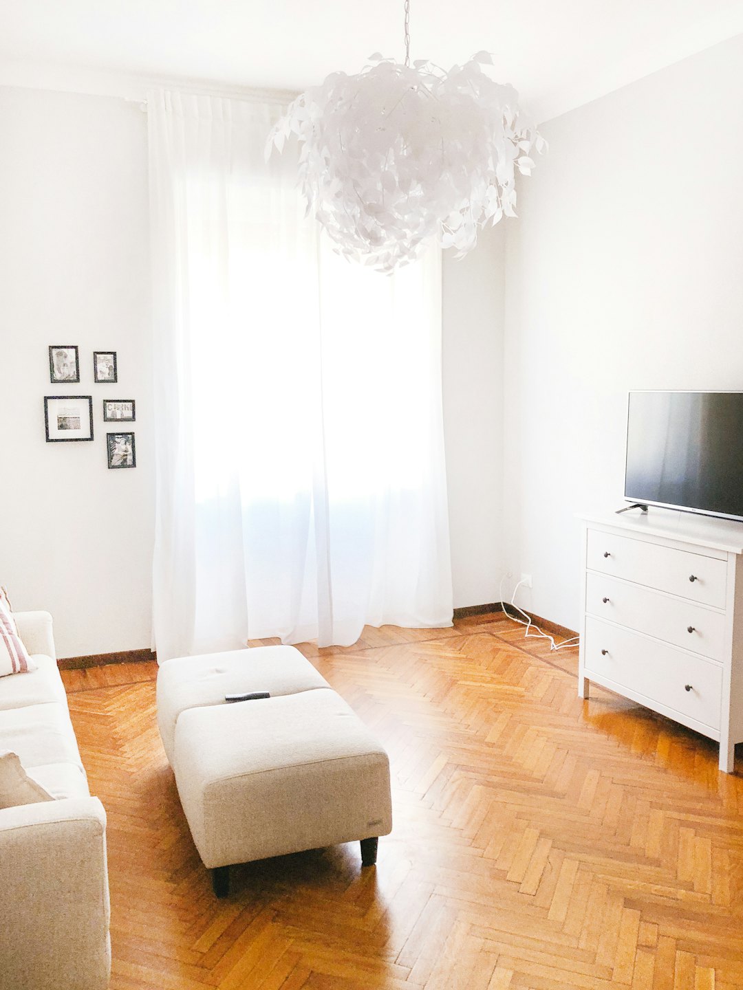 Modern living room with beige sofa and television on dresser.