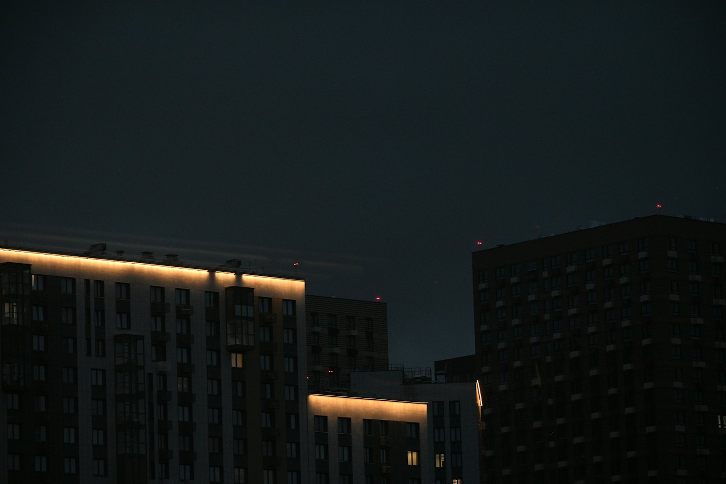Apartment buildings at twilight with illuminated strip lighting.